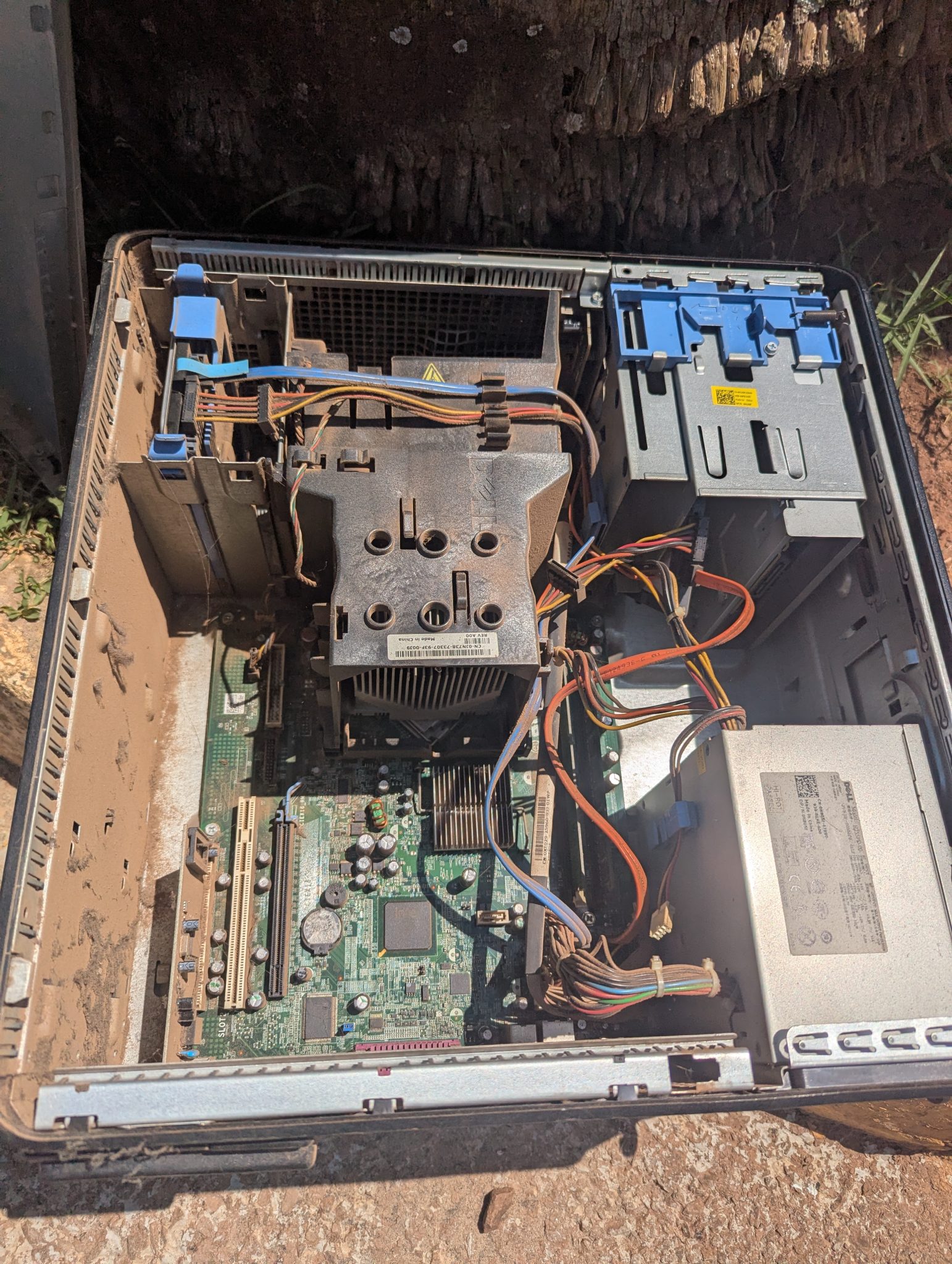 An open desktop computer case showing internal components, including a motherboard, power supply, cables, and a cooling fan.